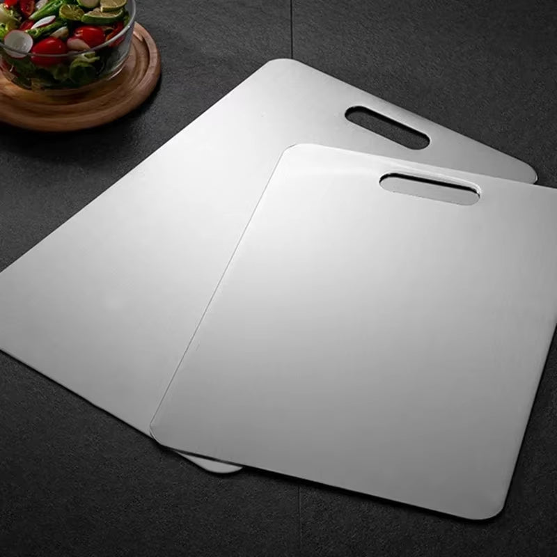 Stainless steel antibacterial cutting board on a kitchen counter with sliced vegetables.