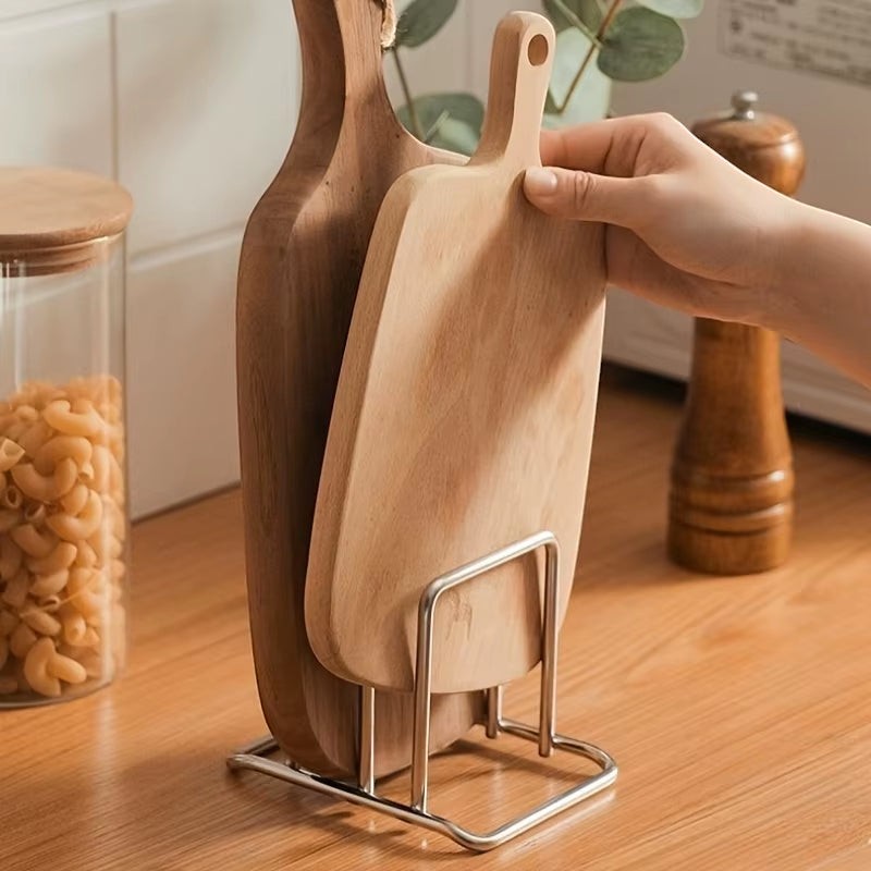 Stainless steel countertop rack organizing pot lids and cutting boards side by side.