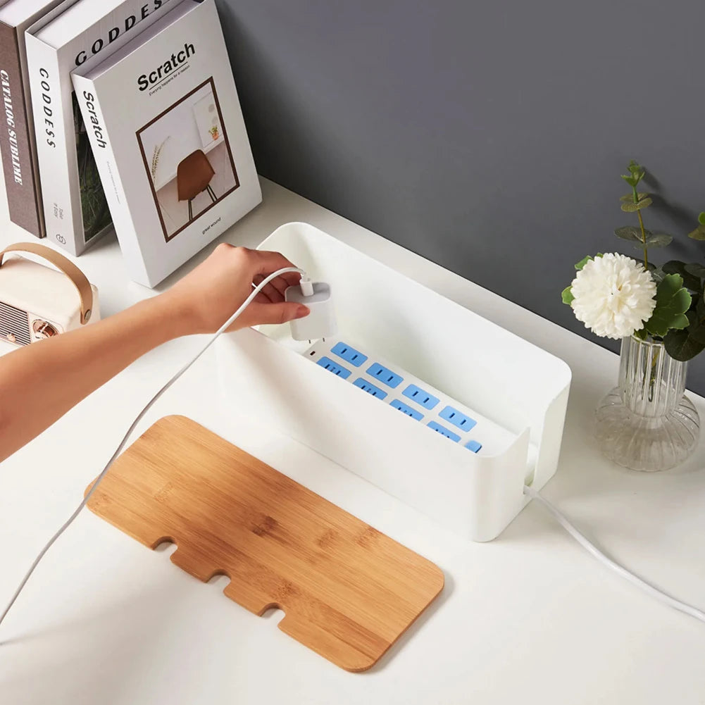 Wooden-style cable management box concealing cords and a power strip under a desk.
