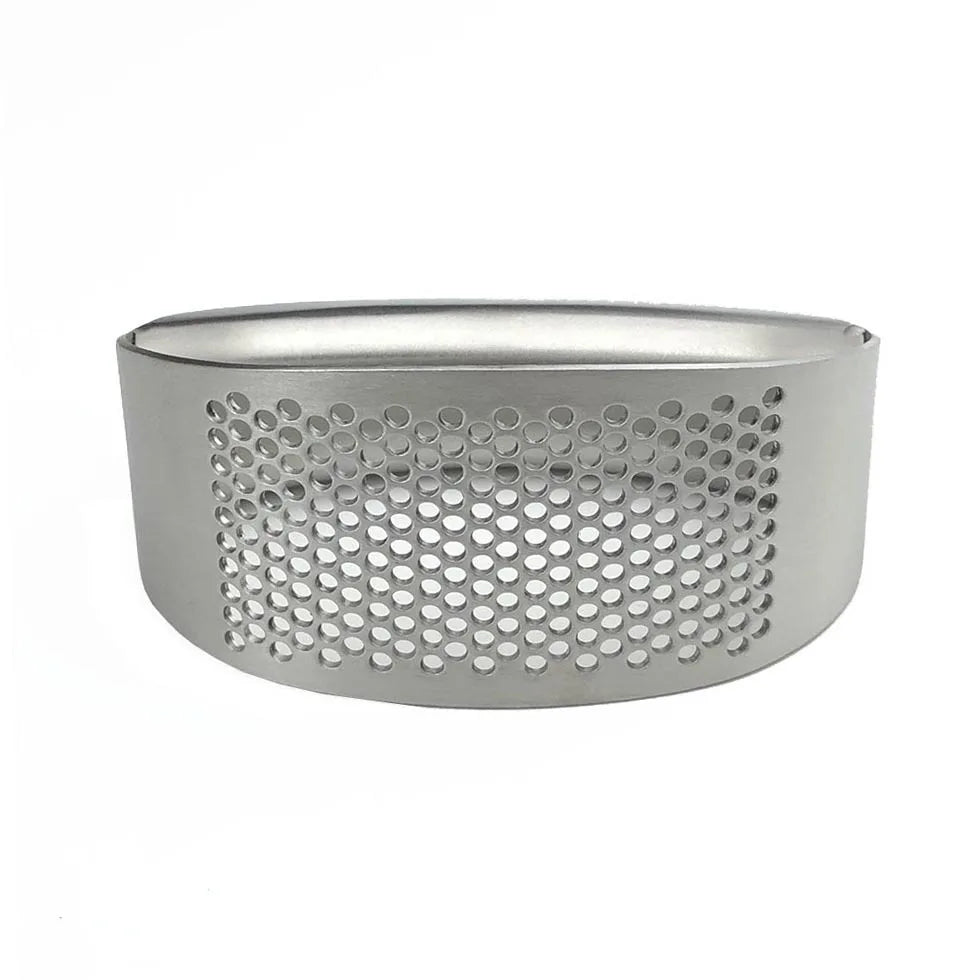 Stainless steel manual garlic press held over a cutting board with minced garlic.