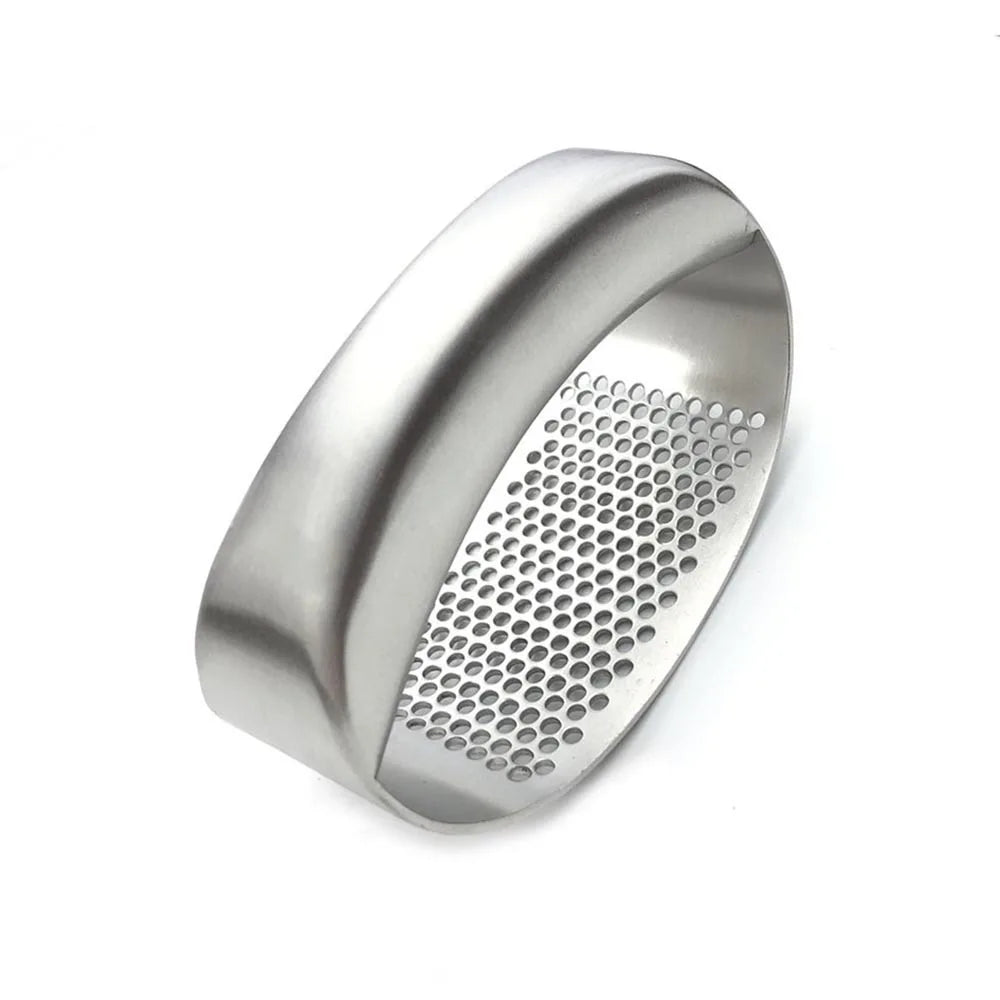 Stainless steel manual garlic press held over a cutting board with minced garlic.