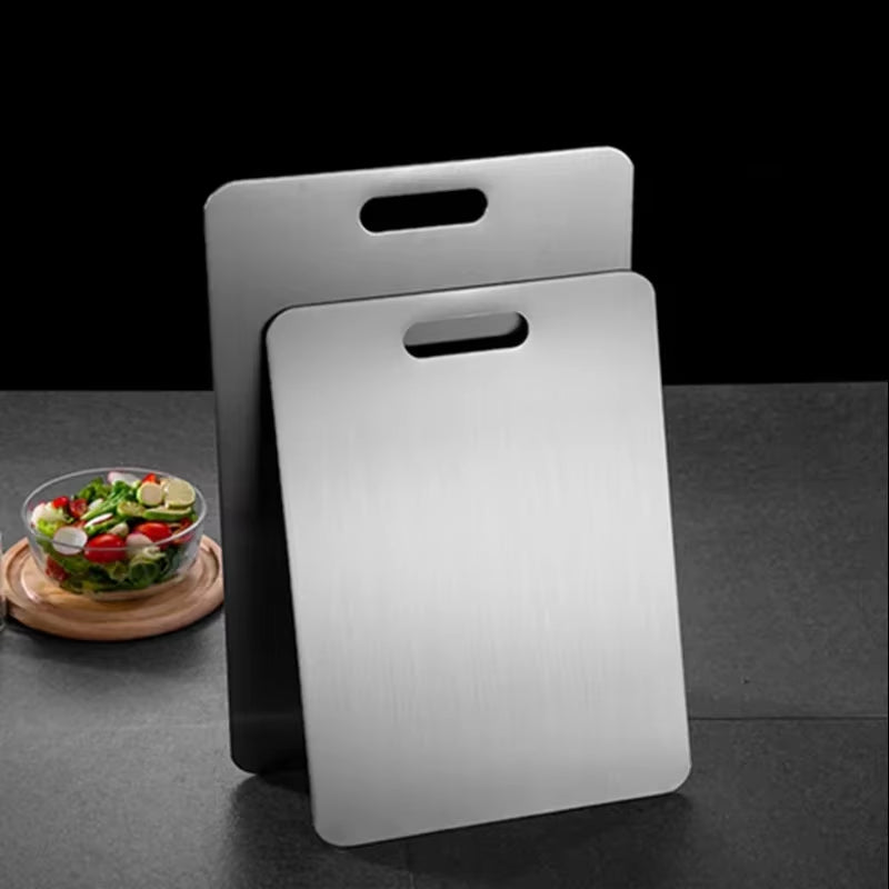 Stainless steel antibacterial cutting board on a kitchen counter with sliced vegetables.