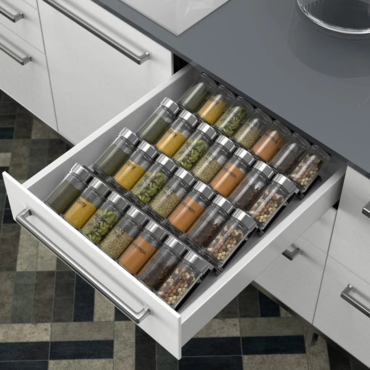 Adjustable acrylic spice organizer tray inside an open kitchen drawer holding spice jars at an angle.