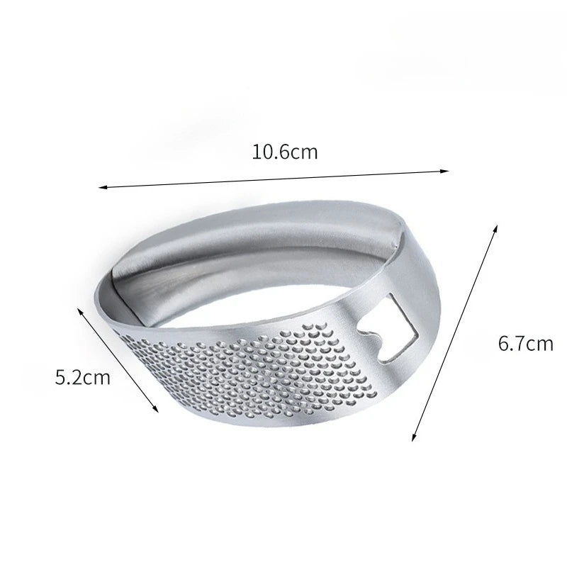Stainless steel manual garlic press held over a cutting board with minced garlic.